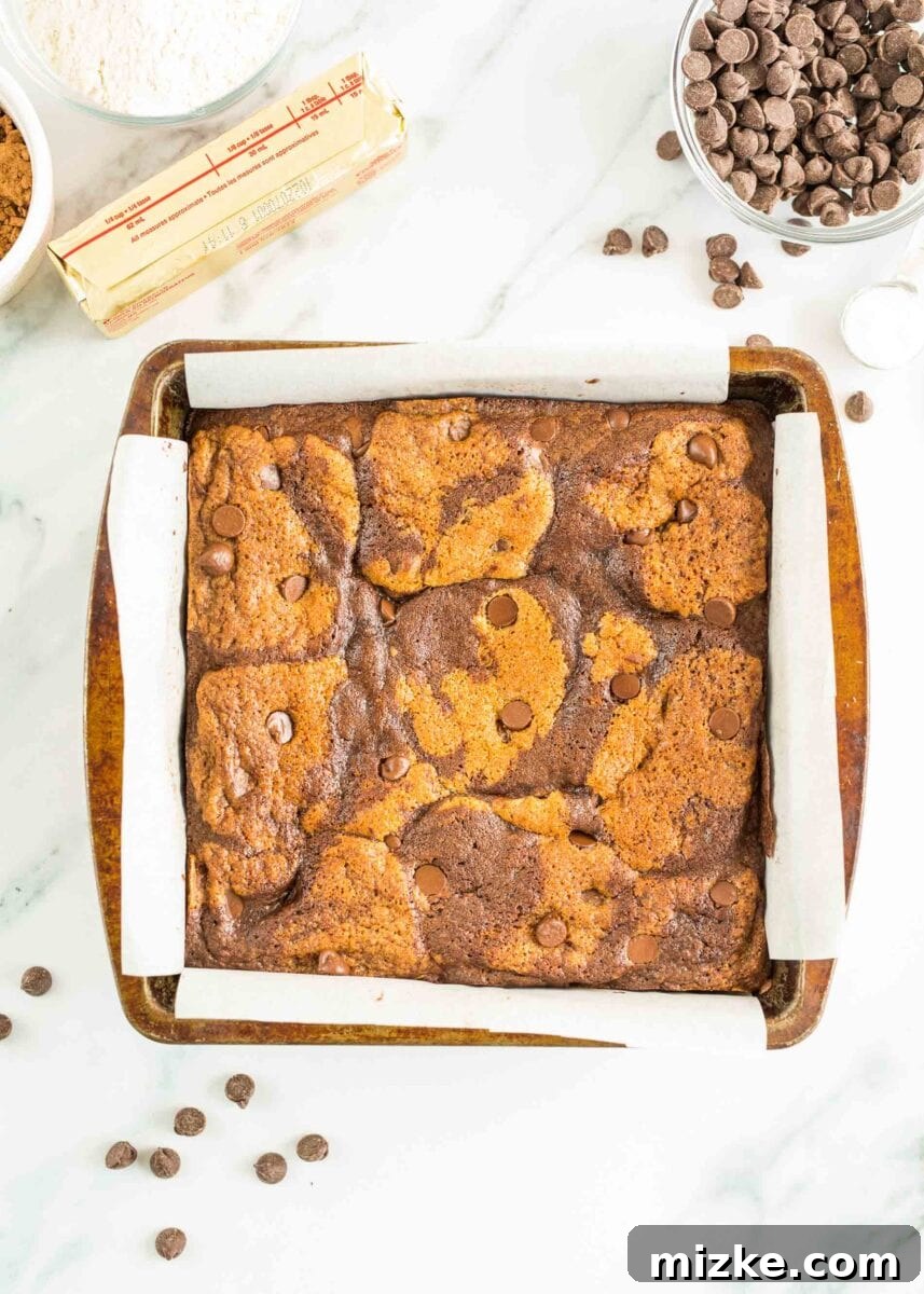 Brownie Cookie Fusion 9 Freshly baked brookies are presented in their square baking dish, displaying a golden-brown cookie top with visible swirls of rich brownie underneath, ready to be sliced.
