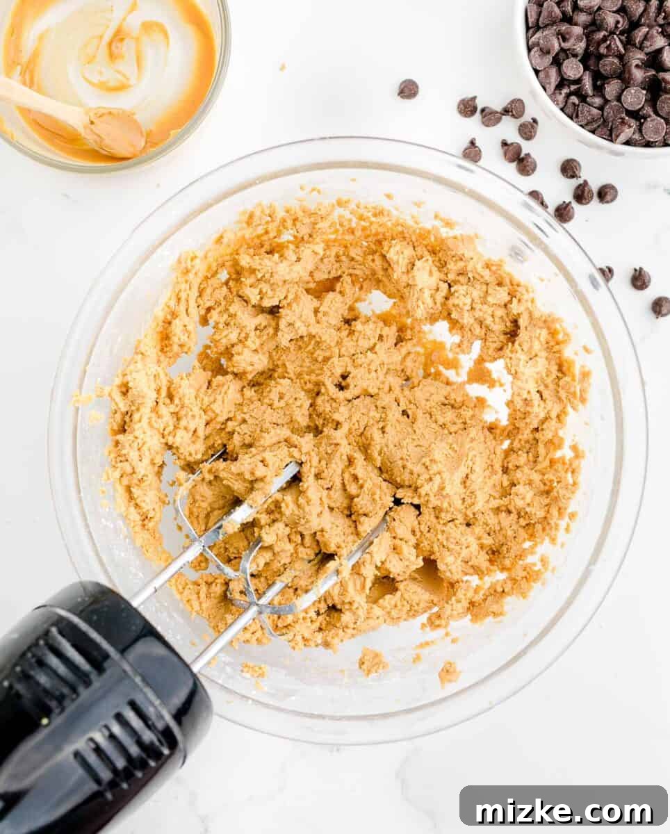 Buckeye Bliss Brownies 7 an electric mixer is beating a peanut butter mixture in a glass bowl