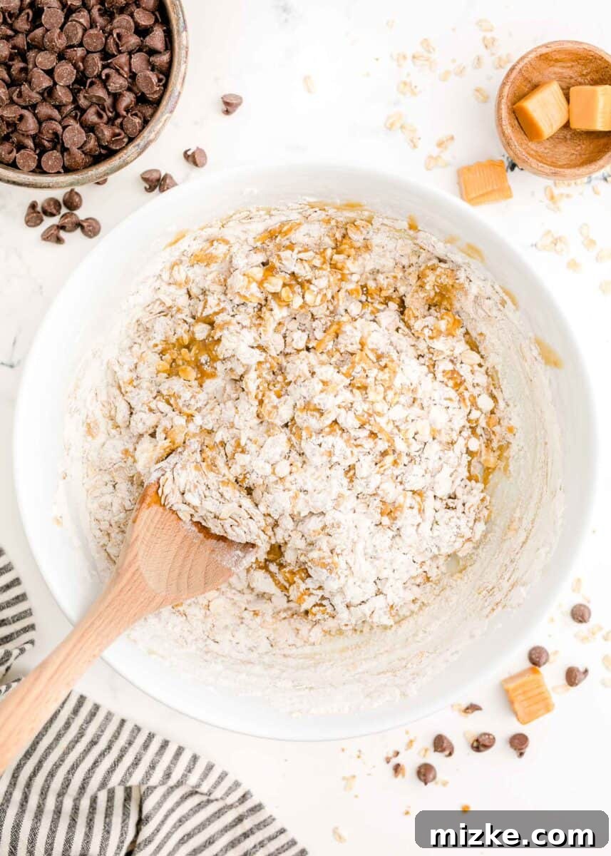 The Carmelitas Legacy 5 The oat crust ingredients are being mixed thoroughly in a glass bowl using a wooden spoon, forming a crumbly texture.