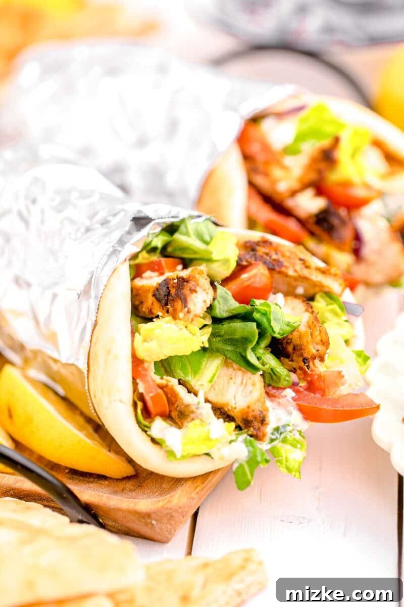 Mediterranean Chicken Wraps 13 a foil wrapped gyro is presented next to a lemon slice.