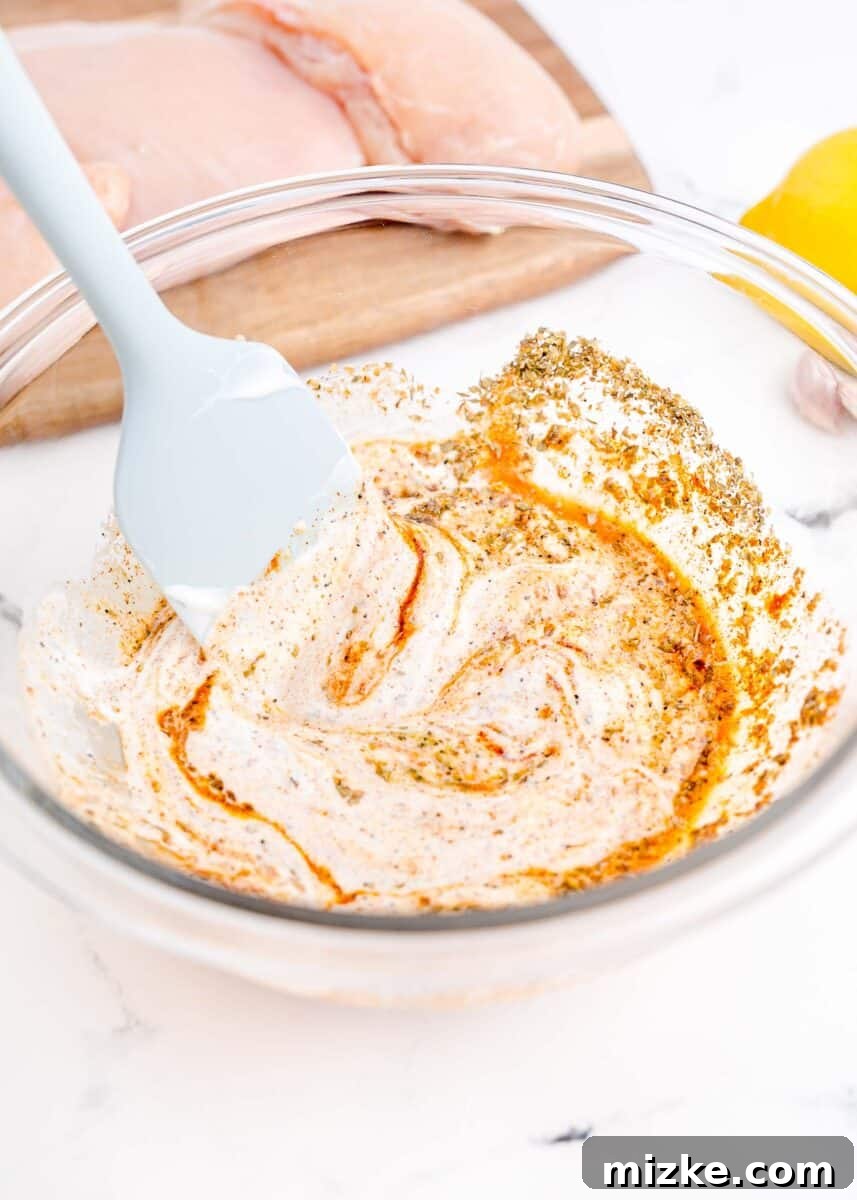 Mediterranean Chicken Wraps 4 a rubber spatula is mixing ingredients together in a bowl.