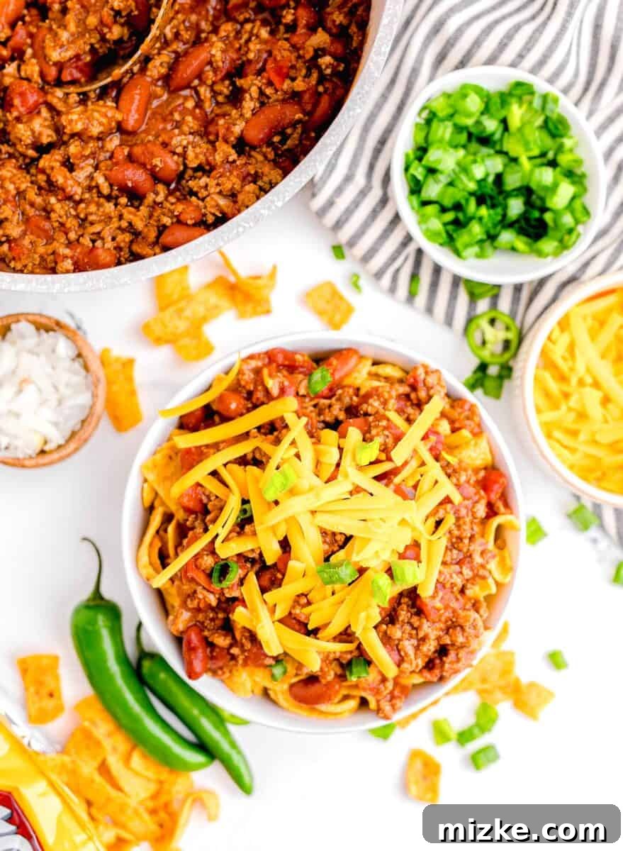 Ultimate Frito Chili Pie 2 Shredded cheddar cheese and green onions are used as garnishes on top of a bowl of chili.