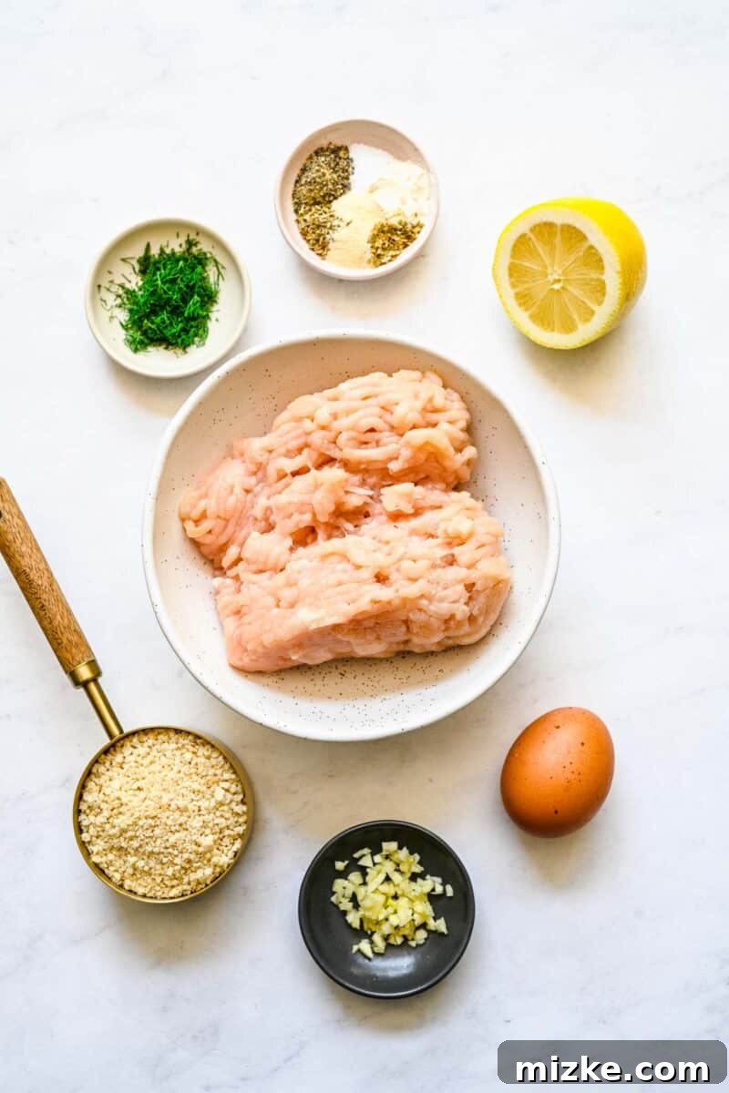 Zesty Greek Chicken Meatballs 3 All the fresh ingredients for Greek chicken meatballs, including ground chicken, lemon, dill, and various spices, laid out on a clean white surface, ready for mixing.