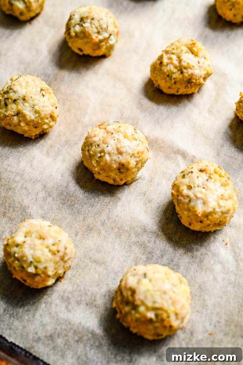 Zesty Greek Chicken Meatballs 7 A baking sheet filled with raw Greek chicken meatballs, uniformly sized and ready for the oven.