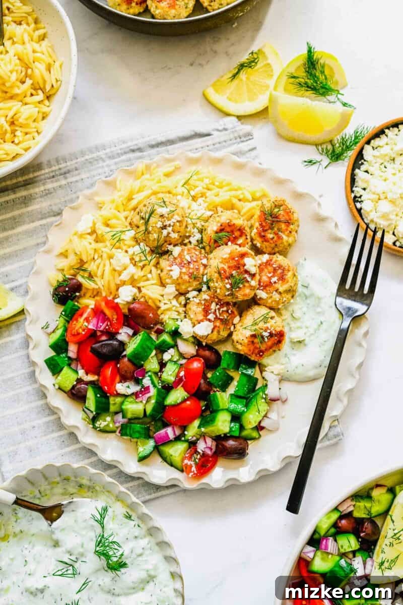 Zesty Greek Chicken Meatballs 8 A beautifully plated meal featuring Greek chicken meatballs, a vibrant summery salad, and fluffy rice, offering a complete and balanced dining experience.