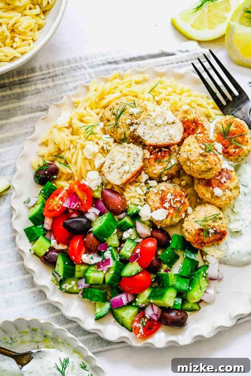 Zesty Greek Chicken Meatballs 10 A balanced and inviting plate featuring golden Greek chicken meatballs, a vibrant side salad, and a bed of rice, ready to be enjoyed.
