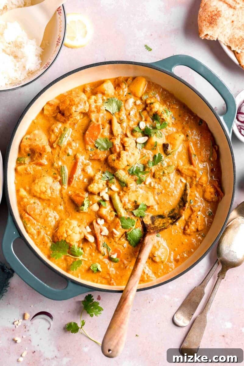 A large blue pot is filled with a rich, creamy vegetable korma, ready to be served, showcasing its inviting texture and color.