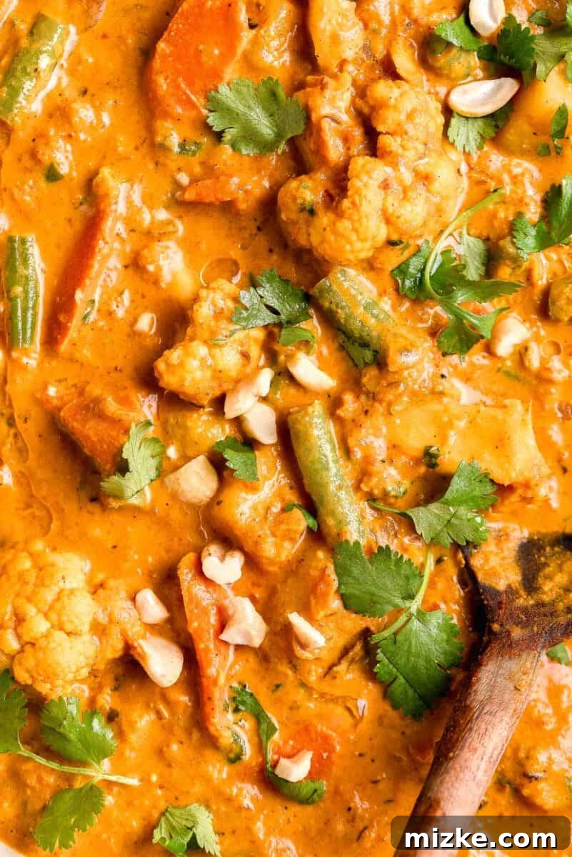 Fresh cilantro leaves elegantly garnish a piping hot bowl of fully cooked vegetable korma, enhancing its vibrant appeal and aromatic finish.