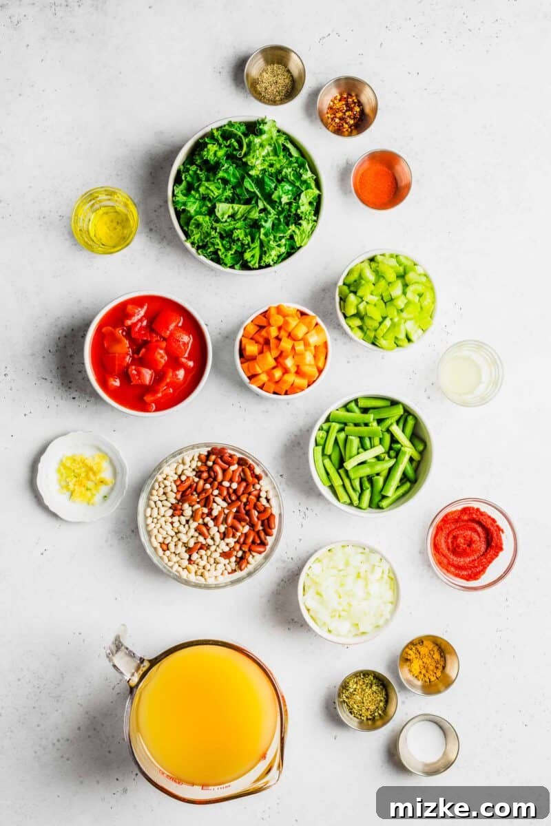 A selection of fresh ingredients for bean soup is neatly arranged on a white surface.