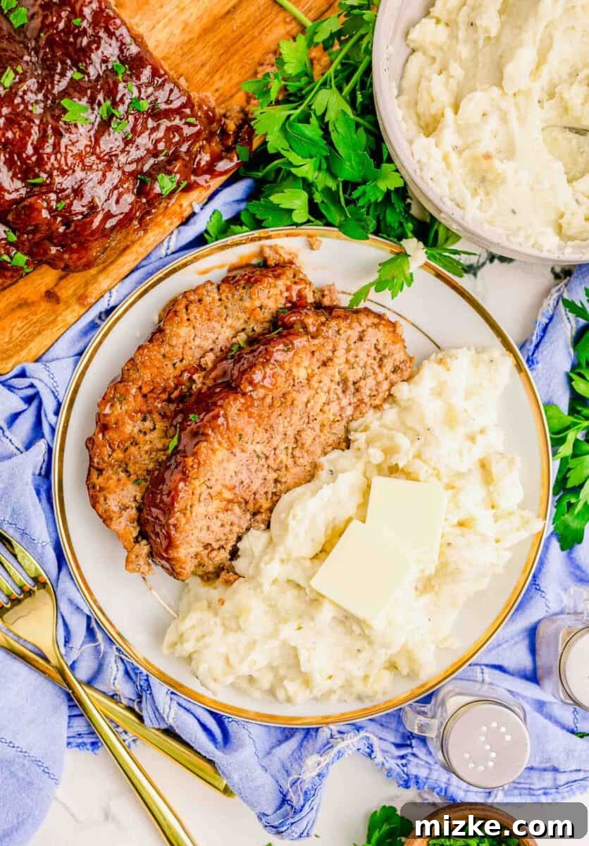 Perfect Instant Pot Meatloaf 13 A hearty serving of Instant Pot meatloaf paired with creamy mashed potatoes, with a larger, almost whole meatloaf loaf in the background, creating a perfect, inviting comfort meal spread.