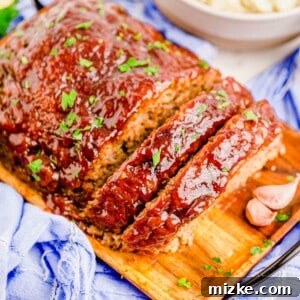 A perfectly sliced meatloaf is placed on a wooden serving plate, ready to be enjoyed with its delicious glaze.