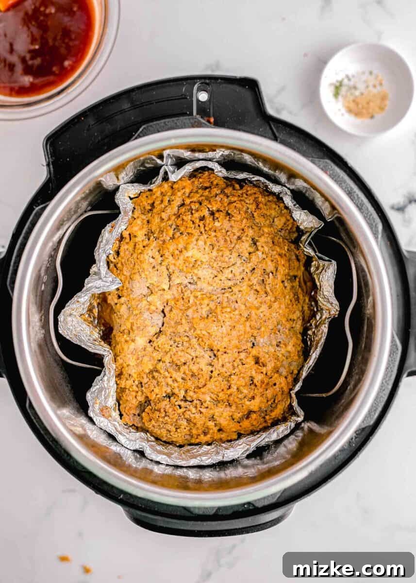 Perfect Instant Pot Meatloaf 7 A perfectly cooked and steaming meatloaf is revealed inside the Instant Pot after the pressure cooking cycle is complete, visibly retaining its shape and moisture.