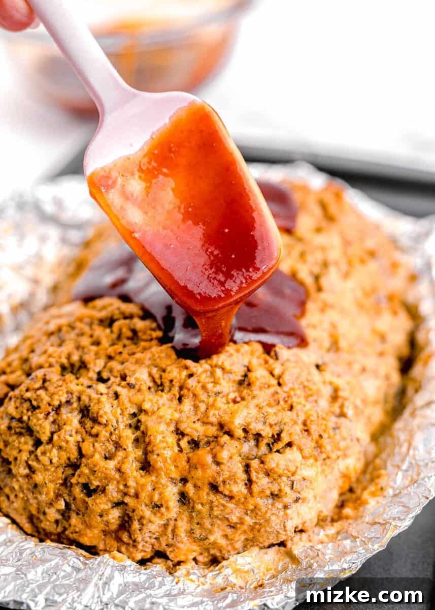Perfect Instant Pot Meatloaf 10 A rich, glossy, and perfectly mixed glaze is being generously drizzled over the top of a freshly cooked meatloaf, promising a flavorful and beautifully caramelized finish.