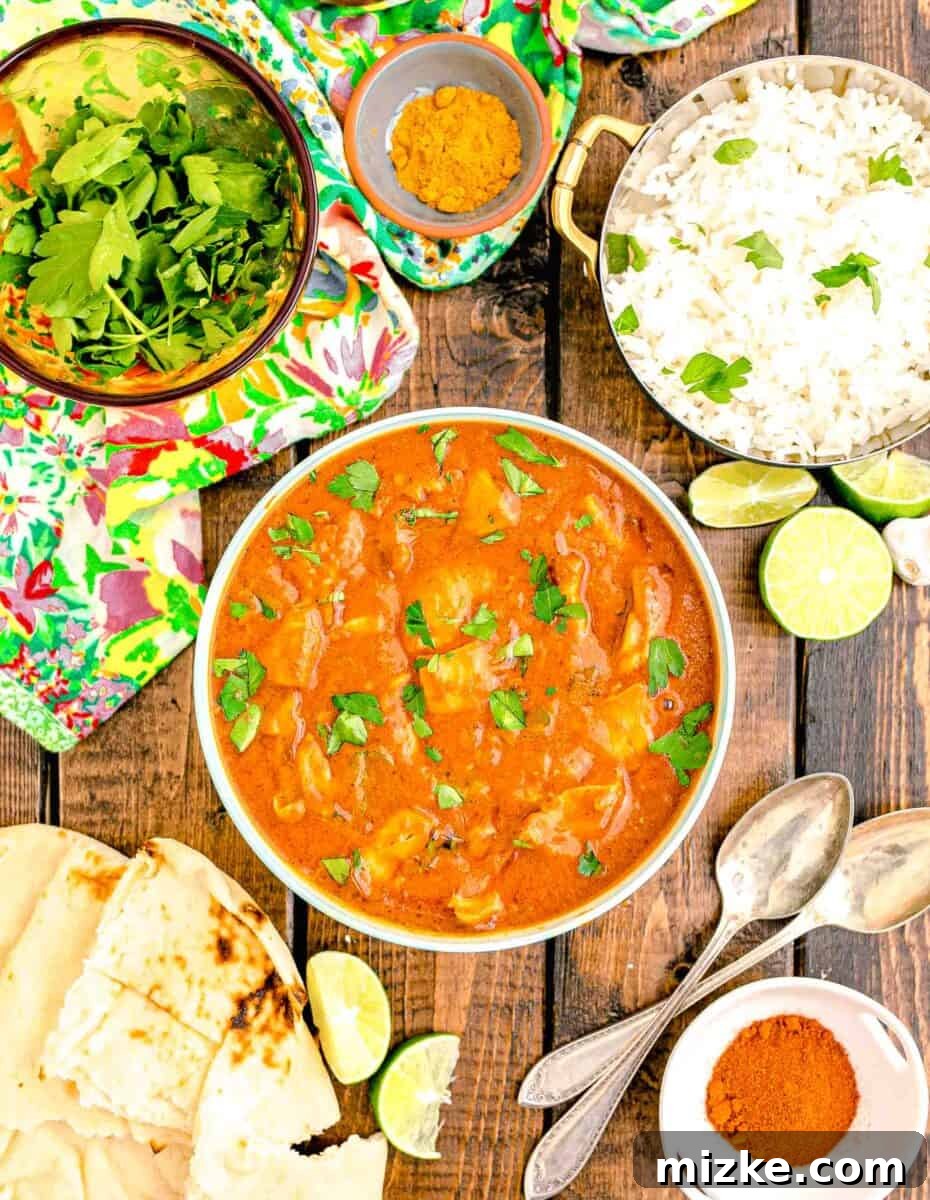 Effortless Crock-Pot Butter Chicken 2 A beautifully presented bowl of slow cooker butter chicken garnished with fresh cilantro, surrounded by fluffy jasmine rice and lime wedges, showcasing its rich texture and vibrant colors.