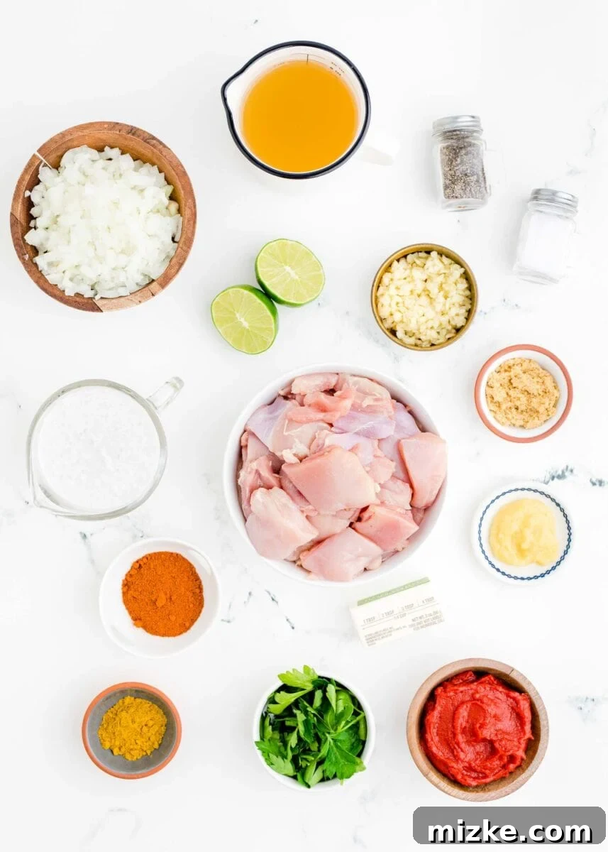 Effortless Crock-Pot Butter Chicken 4 All the fresh, high-quality ingredients for slow cooker butter chicken, including tender chicken thighs, aromatic spices, fresh onion, garlic, ginger, and rich coconut milk, meticulously arranged on a clean white surface.