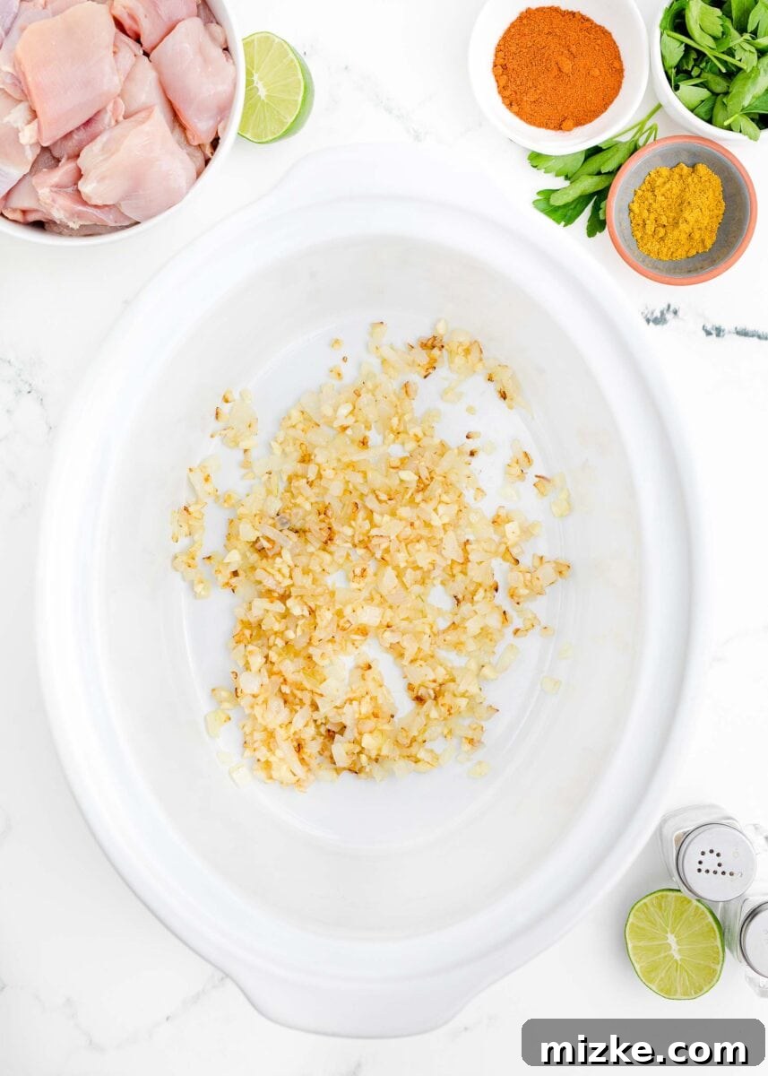 Effortless Crock-Pot Butter Chicken 5 Sautéed diced yellow onions turning translucent and slightly golden in melted butter within a skillet, releasing their sweet aroma and building the dish's flavor base.