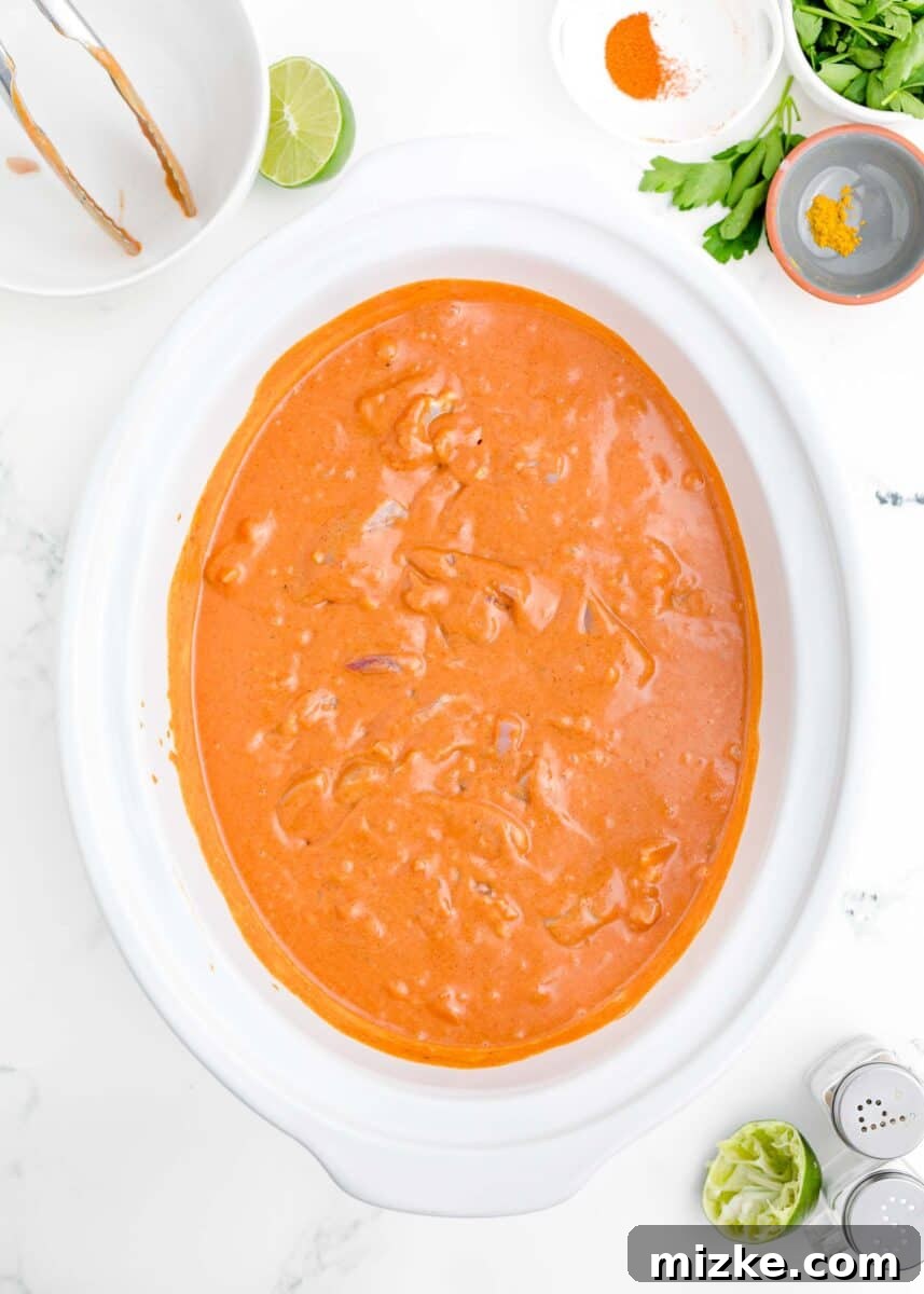 Effortless Crock-Pot Butter Chicken 8 The slow cooker filled with succulent boneless, skinless chicken thighs fully submerged in the creamy, rich butter chicken sauce, evenly coated and ready for the slow cooking process.