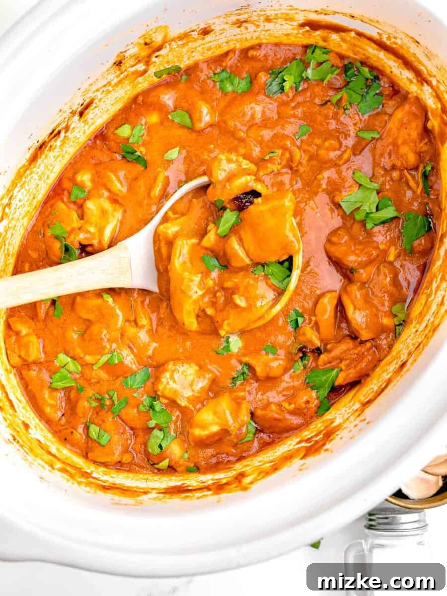 Effortless Crock-Pot Butter Chicken 9 A white ladle scooping a generous portion of the perfectly cooked, creamy slow cooker butter chicken from the Crockpot, showcasing its rich texture, tender chicken, and readiness to be served.