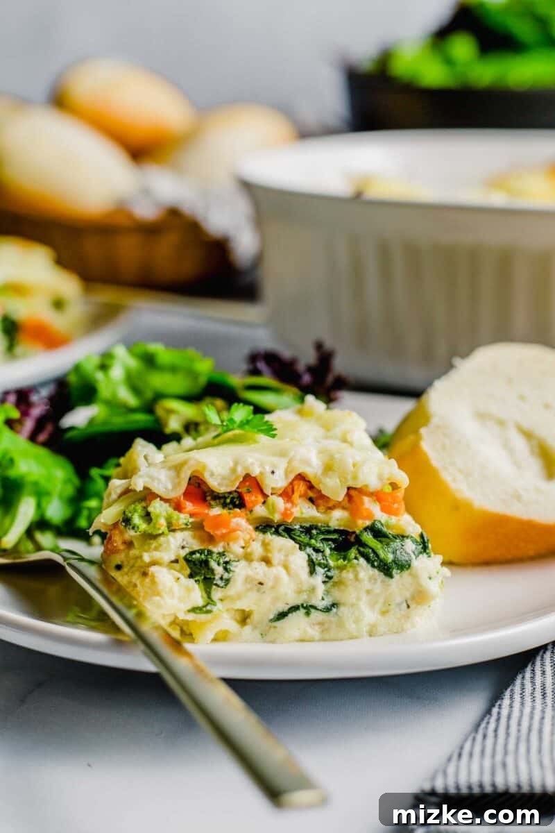A perfectly portioned serving of white sauce lasagna, accompanied by a side of crusty bread and a fresh salad, arranged on a dinner plate.
