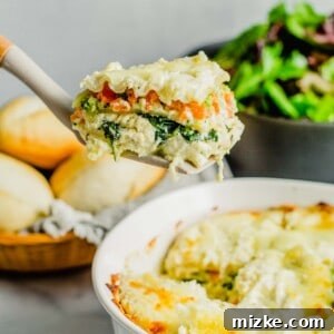 A slice of white lasagna is being lifted from the baking dish.