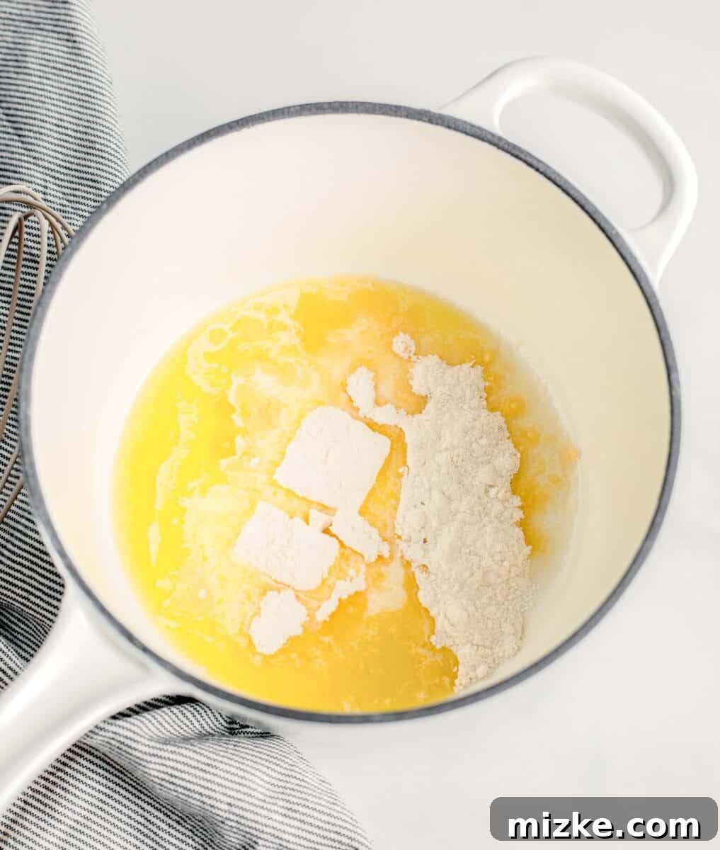 Butter and flour are simmering in a white sauce pot on the stovetop, forming a roux for the béchamel.
