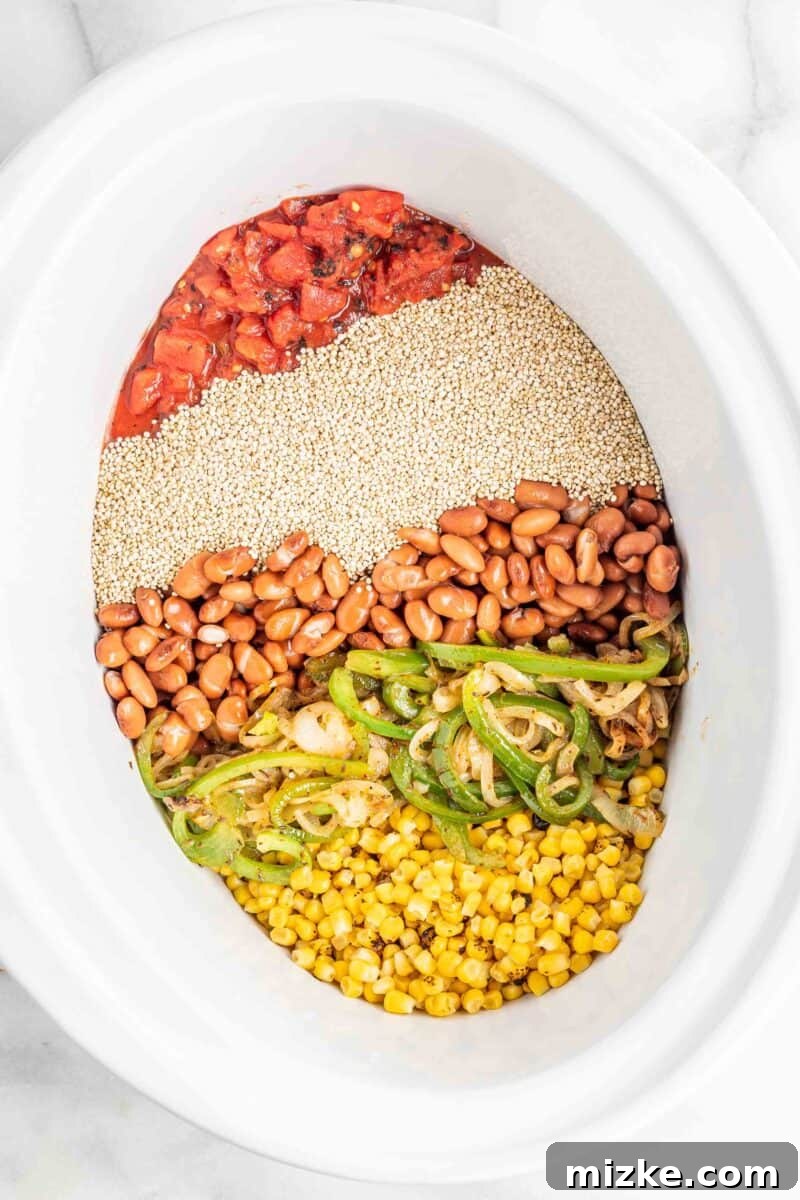 Slow Cooker Fiesta Quinoa Bake 6 All the uncooked ingredients for the enchilada casserole, including quinoa, beans, tomatoes, and corn, are layered into a white Crockpot.