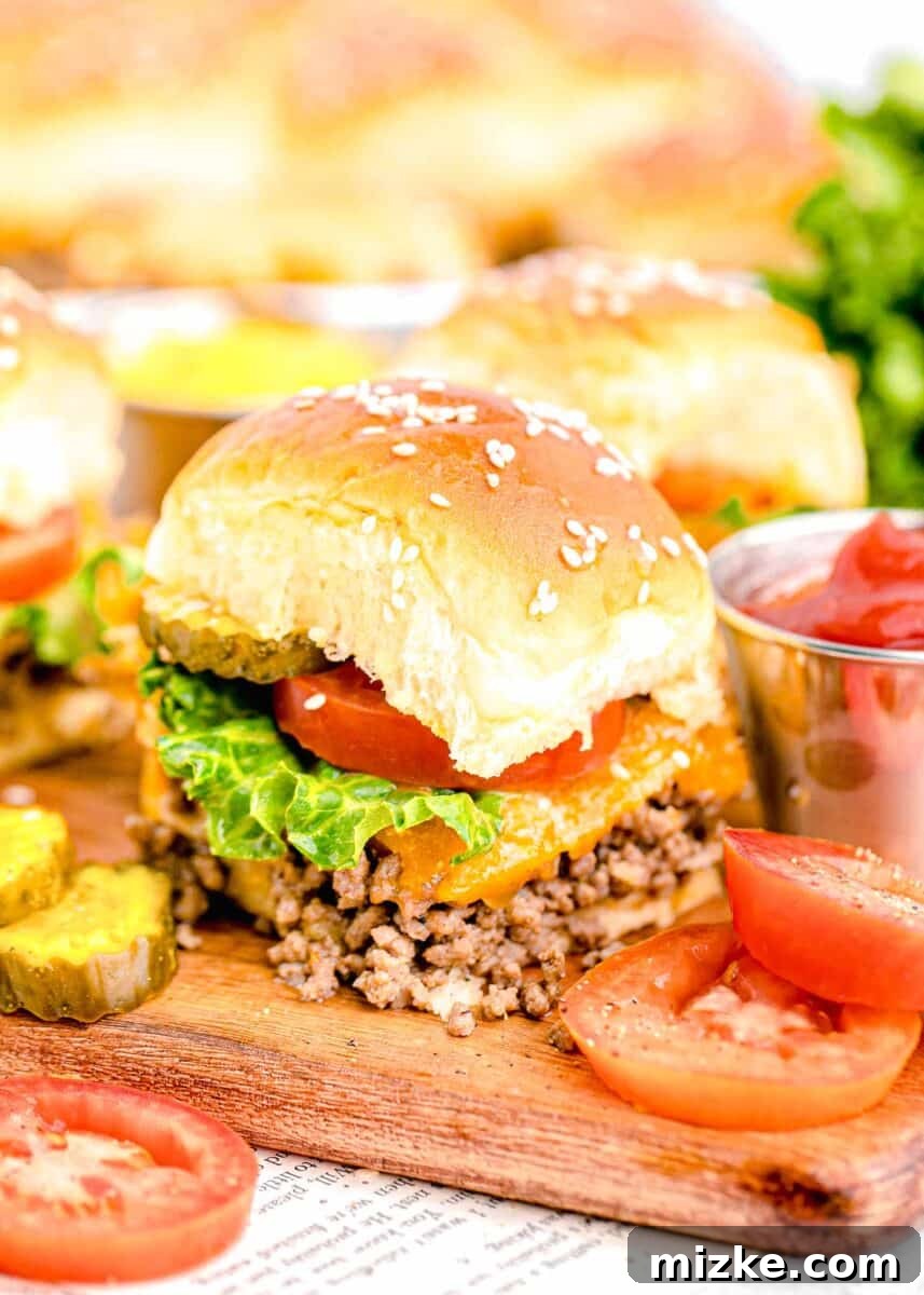 Pint-Sized Patty Perfection 2 A perfectly baked cheeseburger slider sits alongside fresh pickle slices and juicy tomatoes, ready to be devoured.