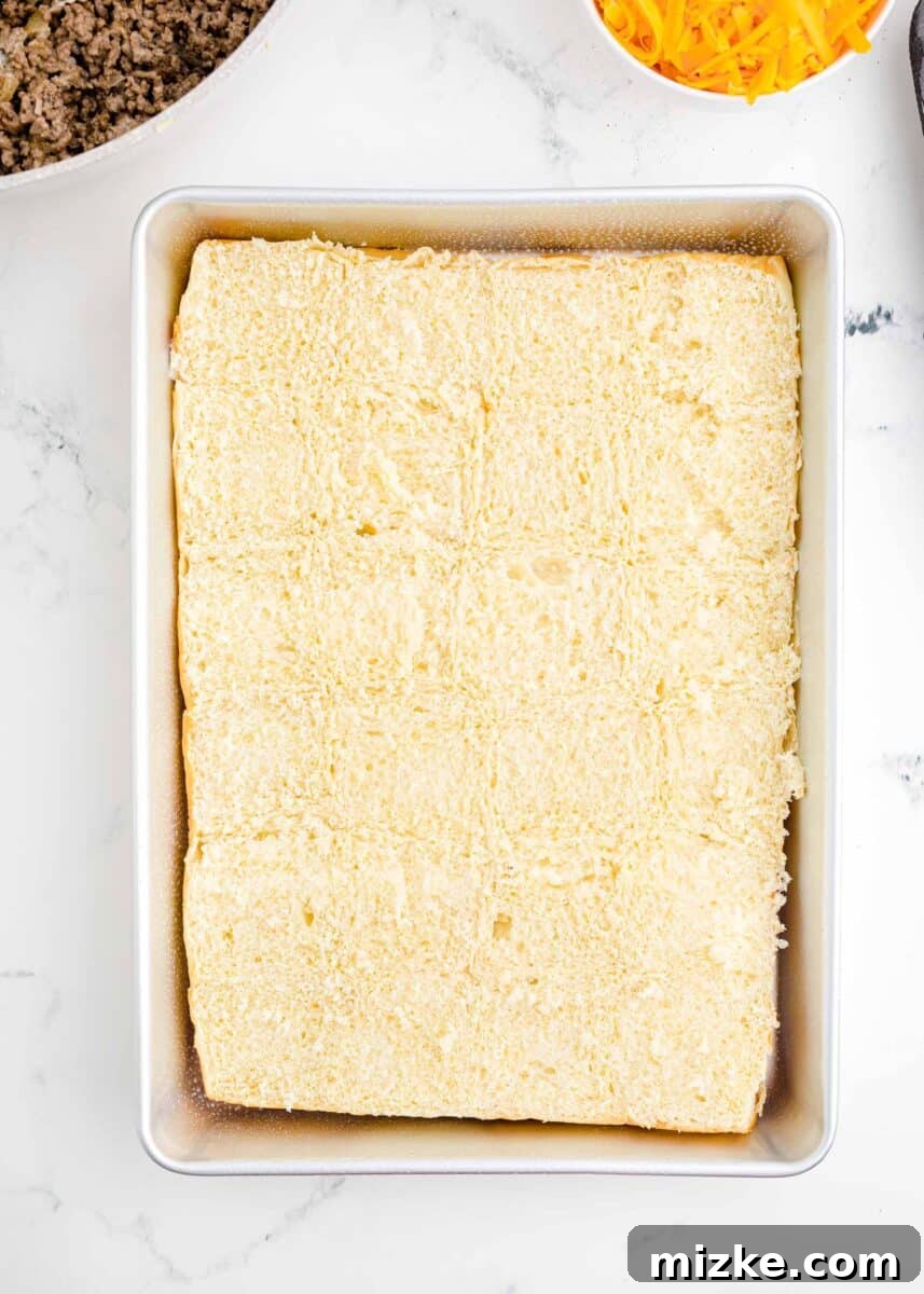 Pint-Sized Patty Perfection 6 The bottom halves of a sheet of bread rolls are perfectly positioned in a baking dish, forming the base of the sliders.