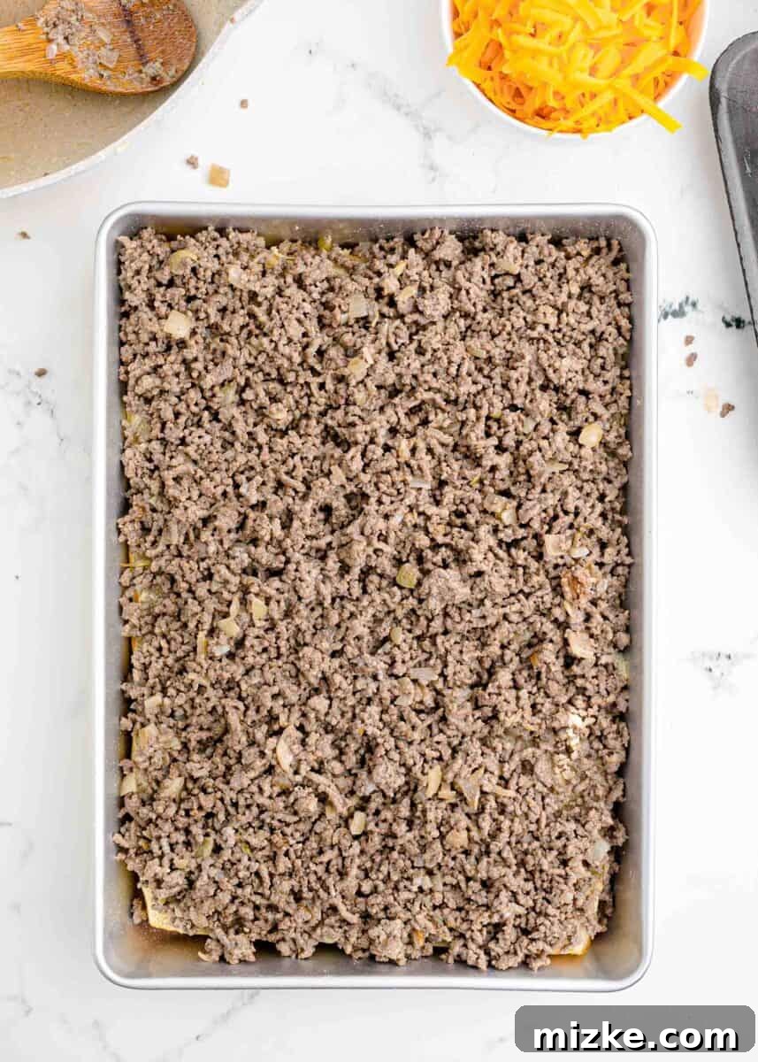 Pint-Sized Patty Perfection 7 A generous, even layer of seasoned cooked ground beef is spread over the bottom bread rolls in the baking dish.