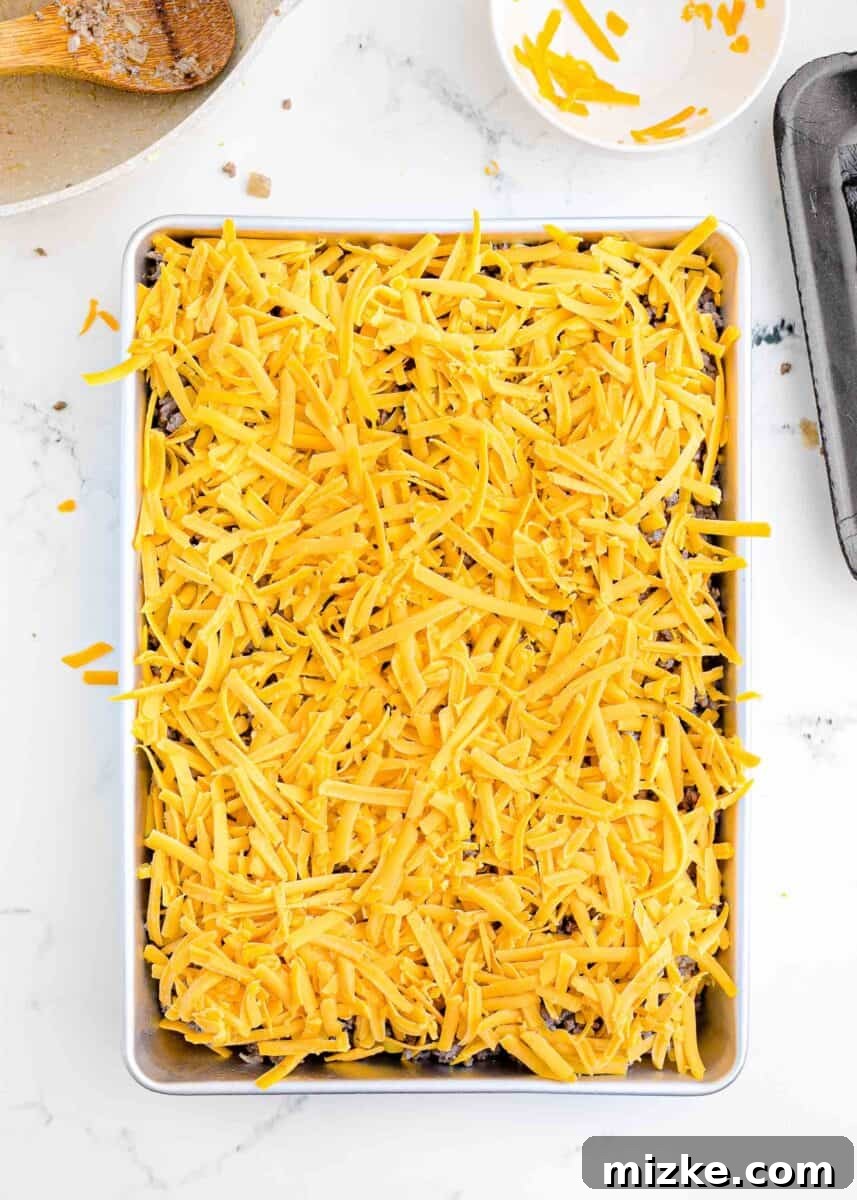 Pint-Sized Patty Perfection 8 A thick layer of shredded cheddar cheese is generously placed on top of the cooked ground beef mixture.
