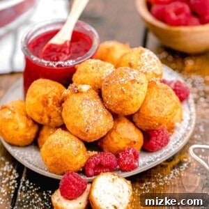 Crispy Cheesecake Poppers 13 A jar of raspberry sauce is placed next to a plate of fried cheesecake bites.