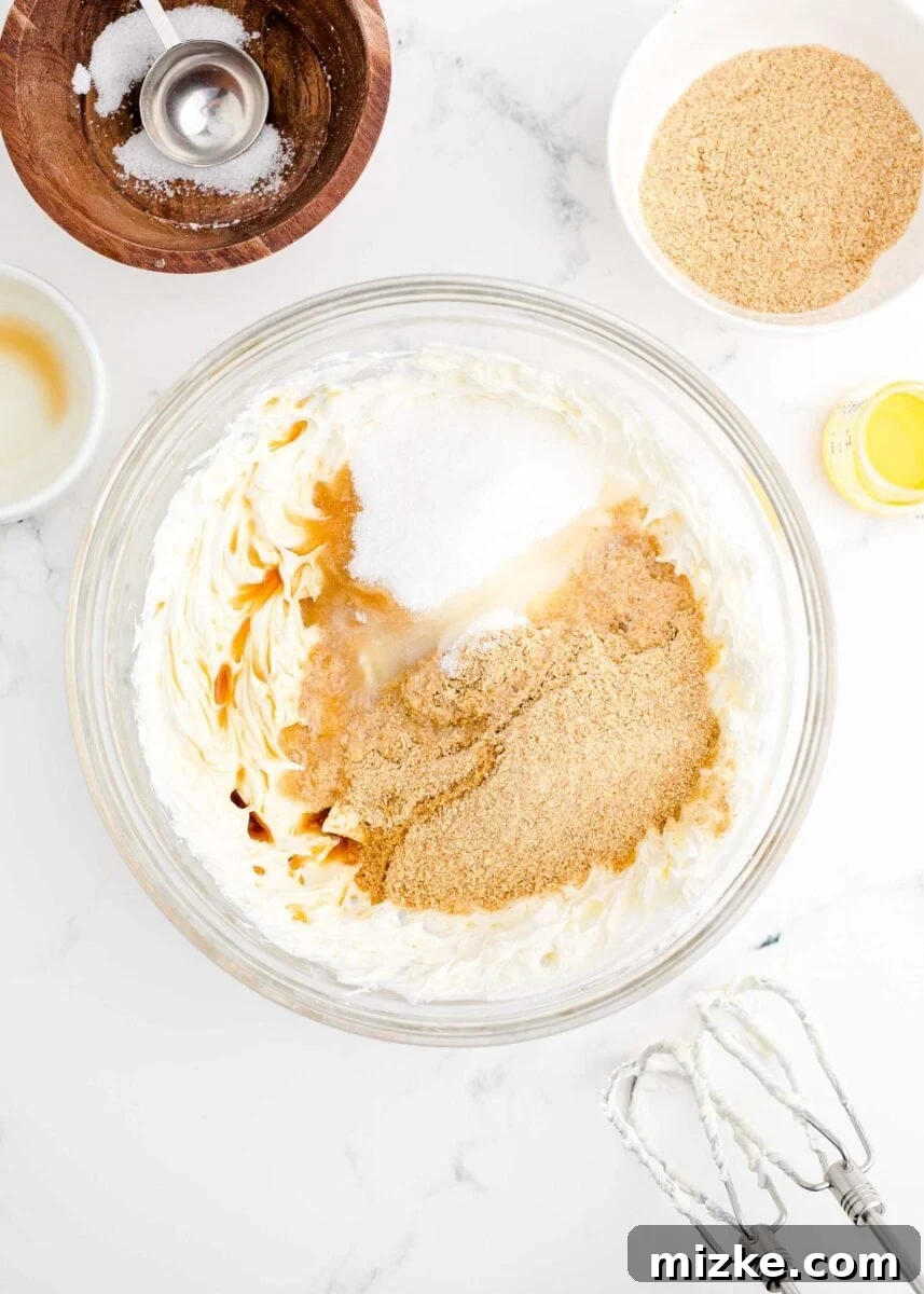 Crispy Cheesecake Poppers 4 Ingredients for the cheesecake filling, including cream cheese, sugar, and crumbs, are combined in a large glass bowl.