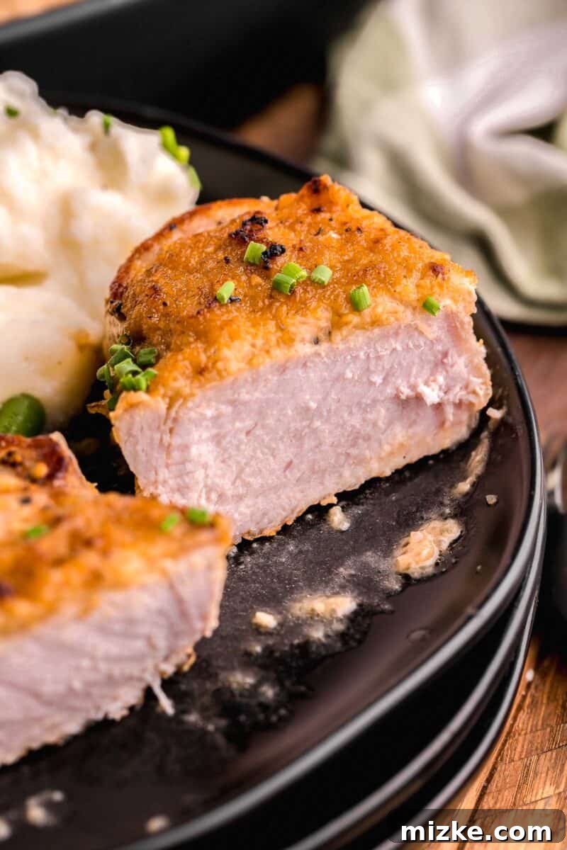 Flavorful Oven Roasted Pork Chops 11 A perfectly cooked oven roasted pork chop, halved to reveal its juicy, tender interior, ready to be enjoyed.
