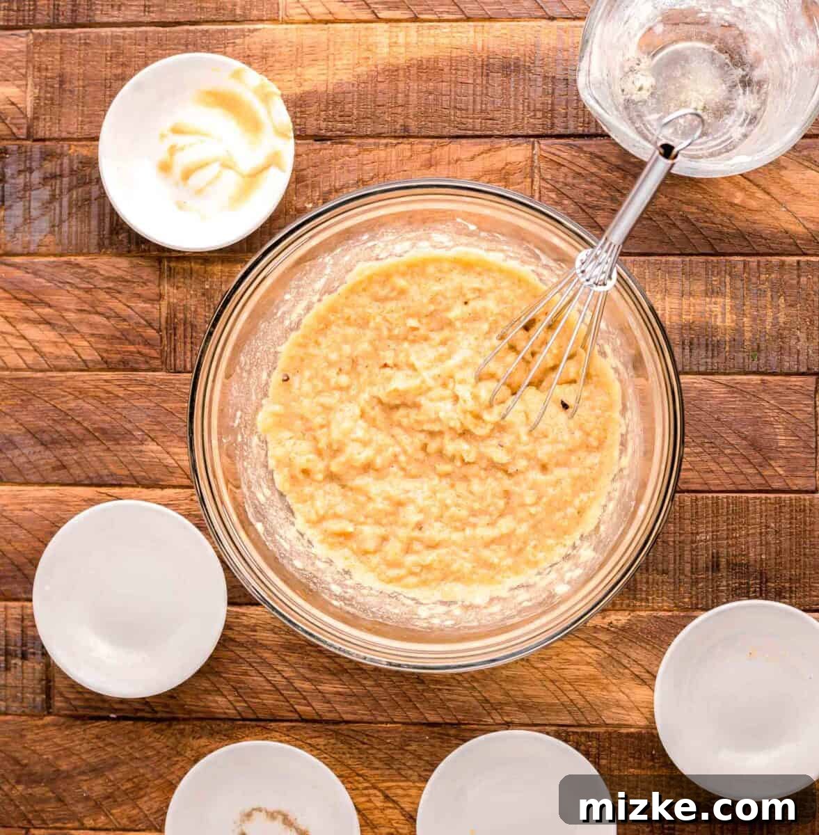Flavorful Oven Roasted Pork Chops 7 A creamy, golden sauce mixture being whisked smoothly in a glass bowl, showcasing its rich texture.