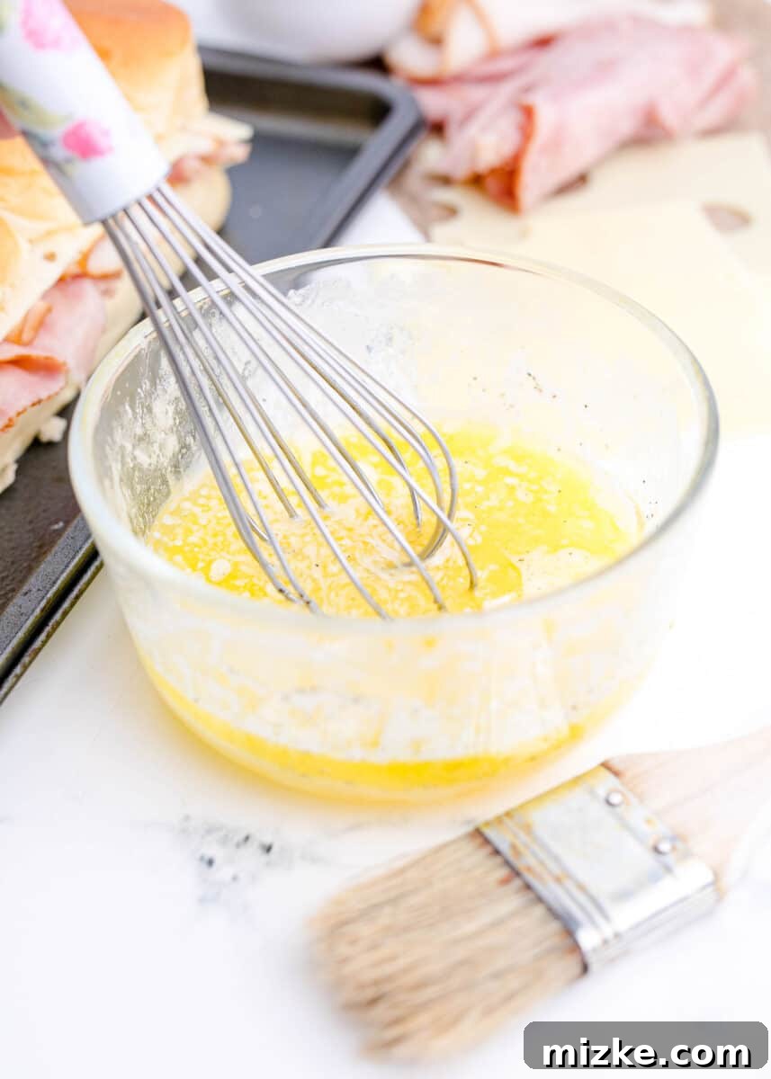 Wet ingredients, including melted butter and a whisked egg, are being combined in a clear glass bowl, creating a smooth mixture.
