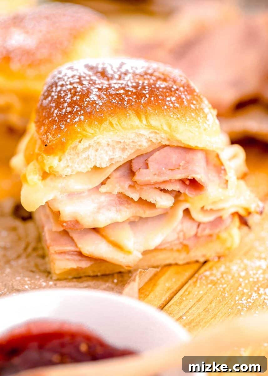 A single, perfectly golden Monte Cristo Slider, dusted with powdered sugar, is presented on a charming wooden surface.