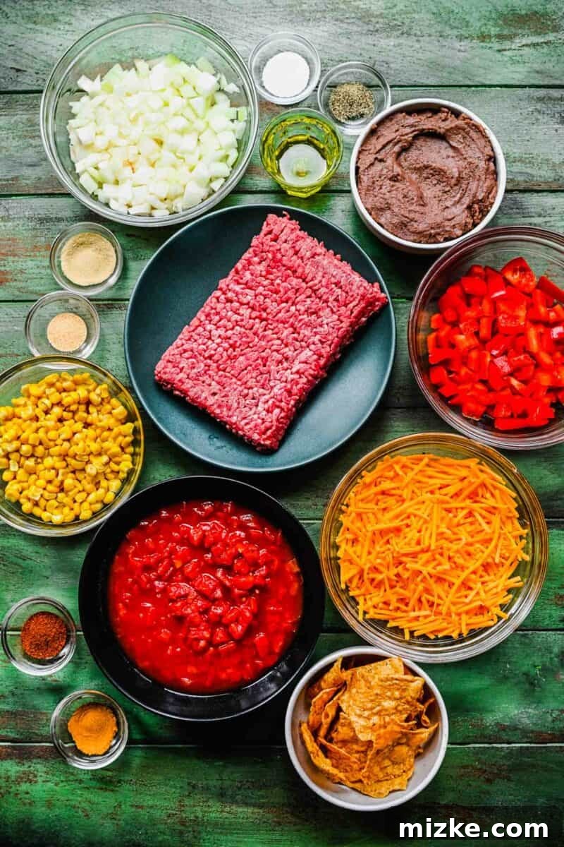 This easy taco casserole recipe is a cheesy, beefy, flavor-packed dinner idea that's ideal for crazy weeknights and parties alike! All the fresh and pantry ingredients for a delicious taco casserole are neatly laid out on a vibrant green surface, ready for assembly.