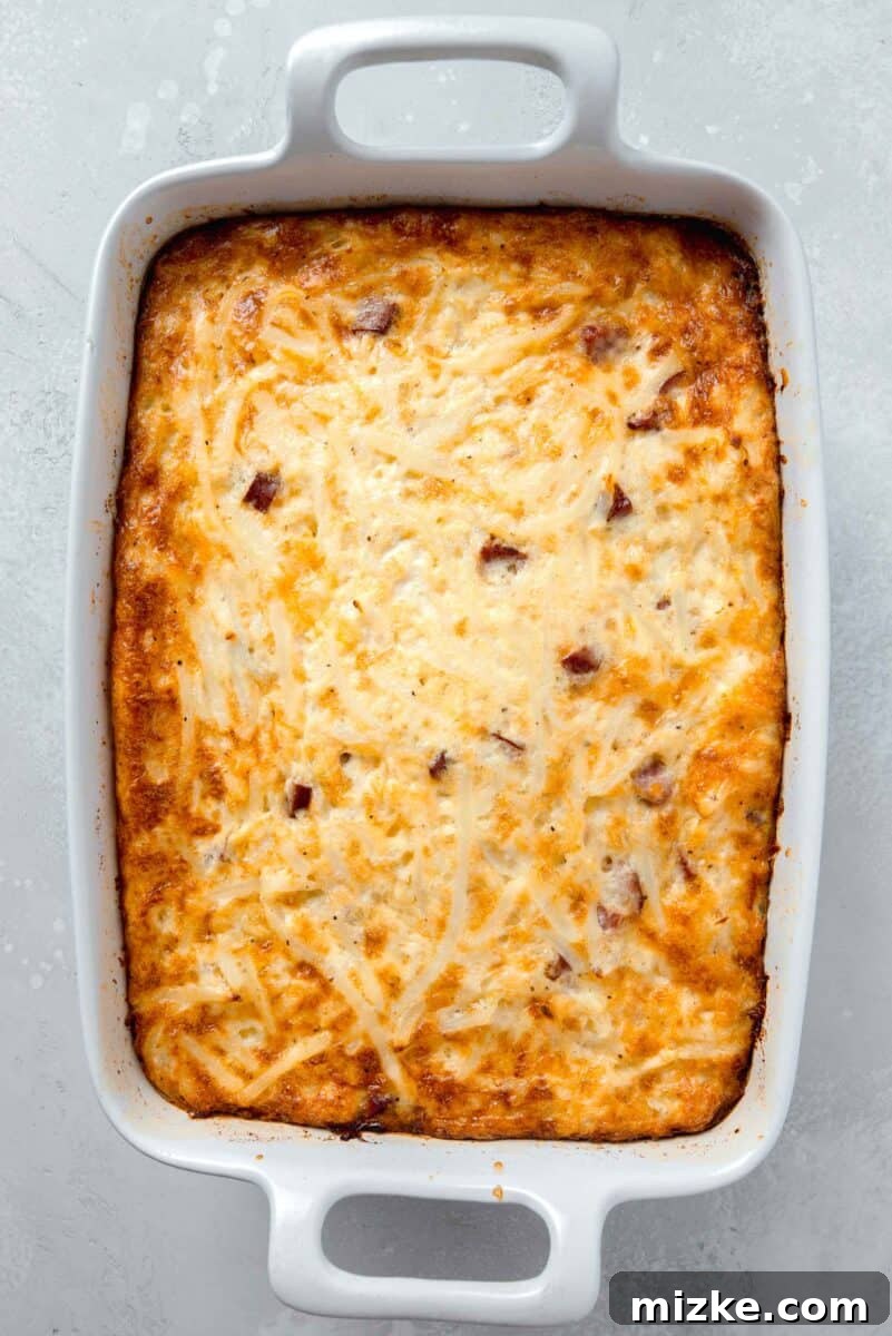 A baked egg white breakfast casserole, boasting a perfect golden-brown top and fluffy texture, resting invitingly in a white 9x13 baking dish, fresh out of the oven.