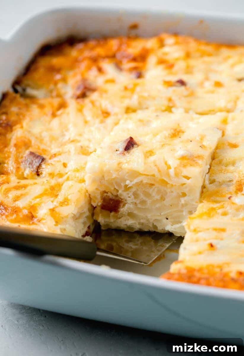 A metal spatula carefully lifting a single, perfectly cut piece of golden-brown egg white breakfast casserole from the baking dish, showcasing its fluffy interior and inviting texture, ready to be served.