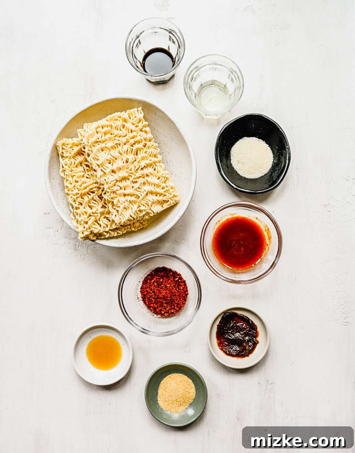 Instant ramen noodles are coated in a full-flavored, spicy sauce in this delicious, quick, and easy buldak ramen recipe. A collection of Buldak ramen ingredients neatly arranged in separate bowls, ready for cooking.