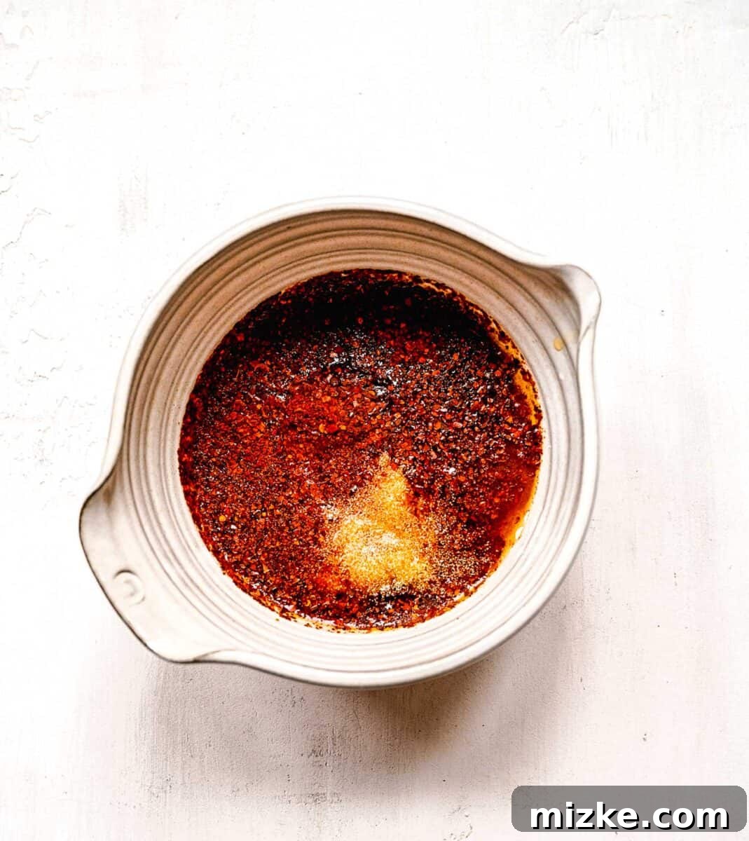 Instant ramen noodles are coated in a full-flavored, spicy sauce in this delicious, quick, and easy buldak ramen recipe. The initial step of making Buldak ramen sauce, with ingredients being mixed in a bowl.