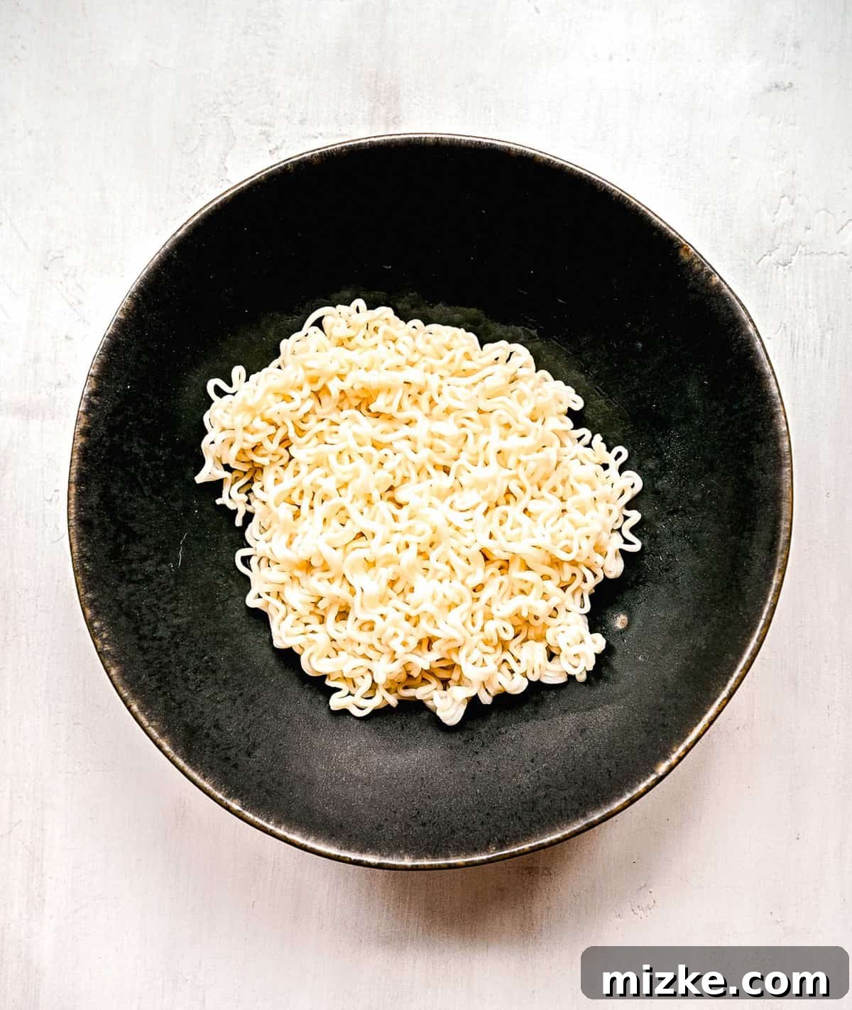 Instant ramen noodles are coated in a full-flavored, spicy sauce in this delicious, quick, and easy buldak ramen recipe. Perfectly cooked ramen noodles, drained and ready for sauce, showcasing their springy texture.