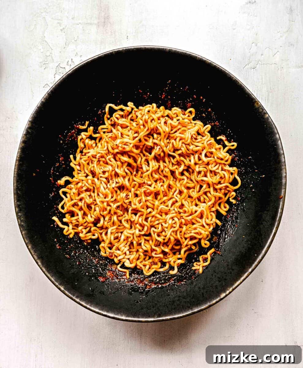 Instant ramen noodles are coated in a full-flavored, spicy sauce in this delicious, quick, and easy buldak ramen recipe. The ramen noodles fully coated in the vibrant red Buldak sauce, glistening and ready for toppings.