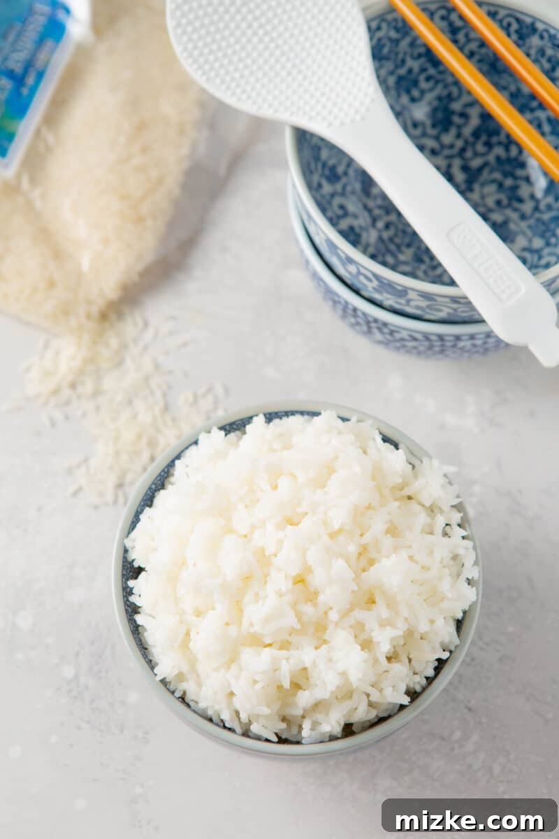 Perfect Instant Pot Jasmine Rice 3 Overhead shot of fluffy Instant Pot Jasmine rice alongside a traditional rice paddle and a pile of uncooked jasmine rice grains