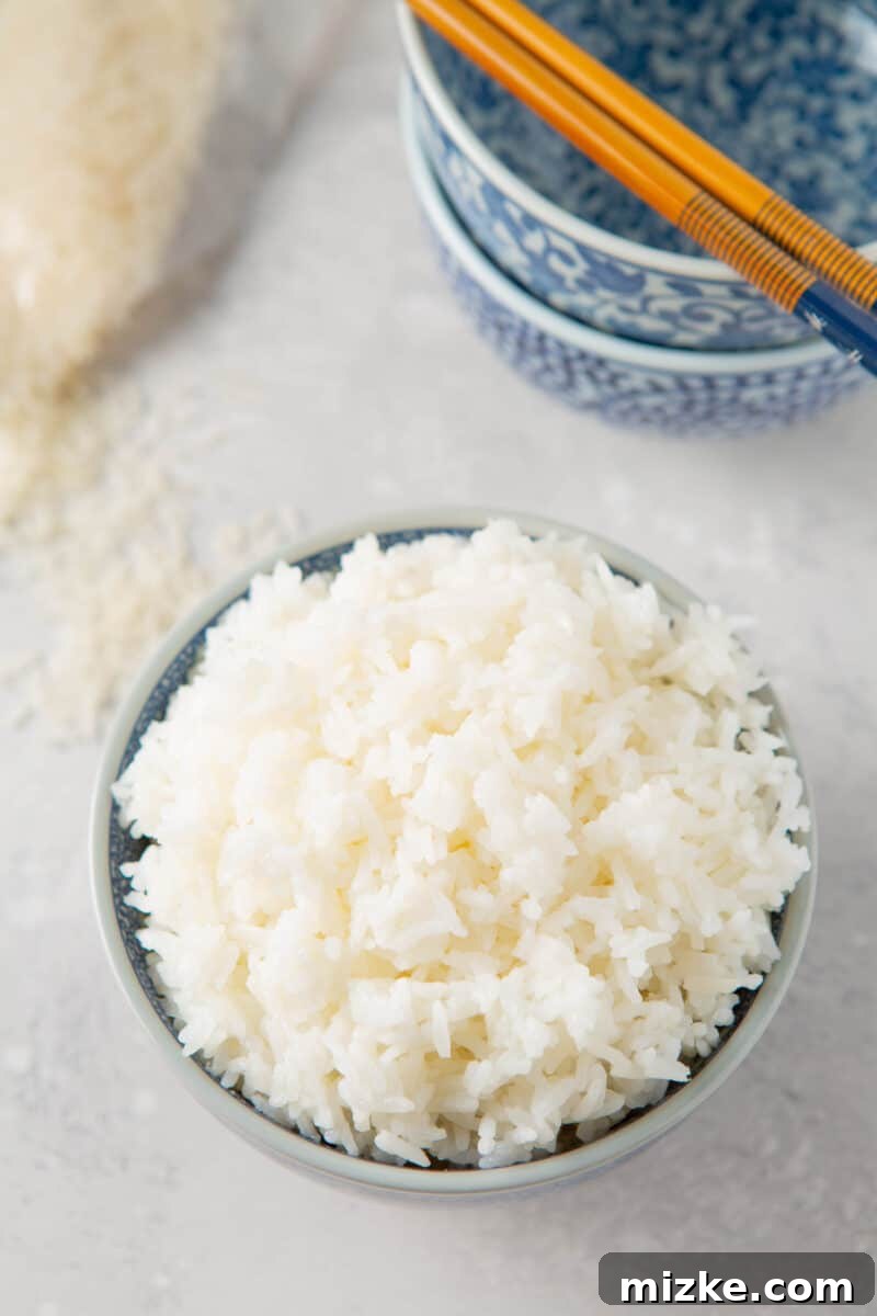 Perfect Instant Pot Jasmine Rice 9 Instant Pot Jasmine rice in a bowl, surrounded by other empty blue bowls and chopsticks, ready for an Asian feast