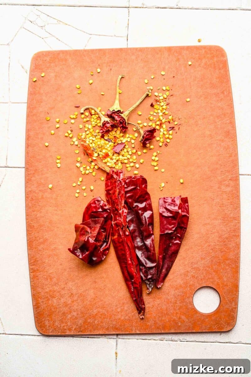 Bold Chipotle Guajillo Garlic Steak 5 Removing the stems and seeds from guajillo peppers on a cutting board.