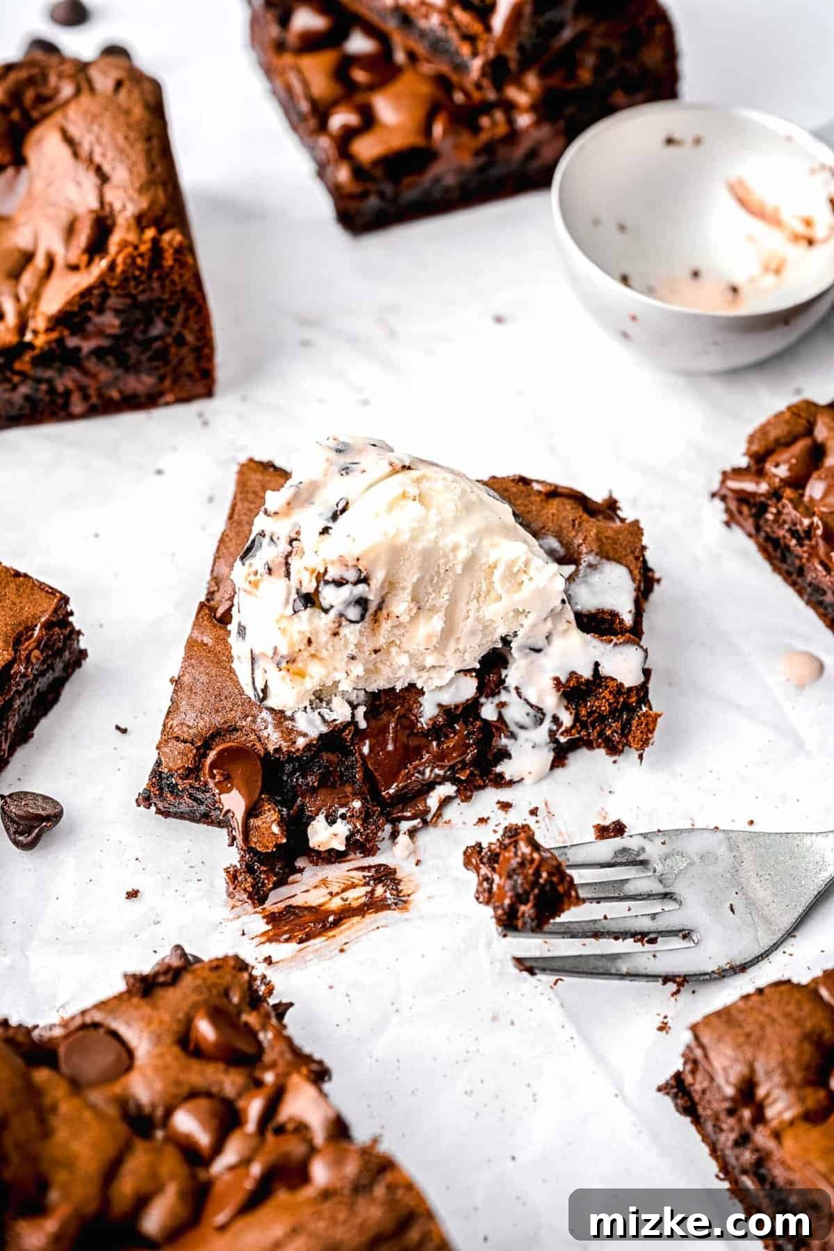 These cake mix brownies turn baking into a walk in the park. Made with 5 ingredients in 30 minutes, they're sure to become a new favorite. Cake mix brownies cut into squares. One has a scoop of vanilla ice cream on top and a bite taken out of it, showing its soft interior.