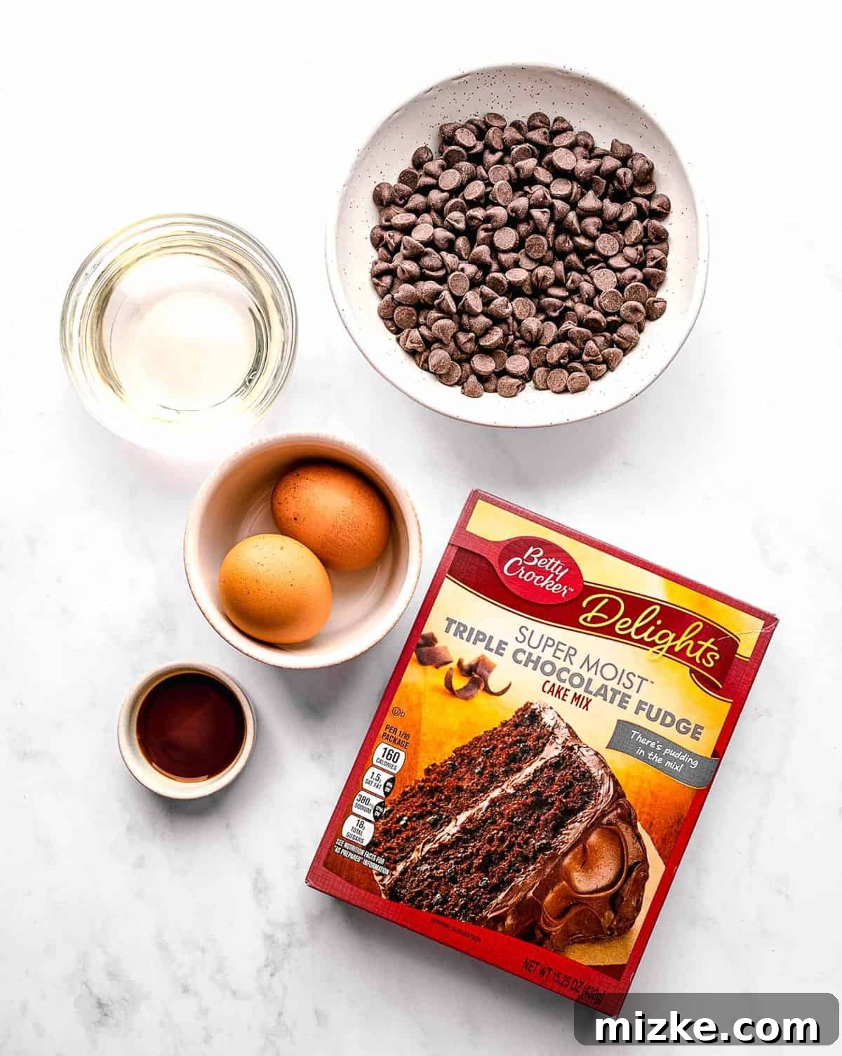 These cake mix brownies turn baking into a walk in the park. Made with 5 ingredients in 30 minutes, they're sure to become a new favorite. Ingredients for cake mix brownies set out on a wooden work surface, including a box of cake mix, oil, eggs, vanilla extract, and chocolate chips.