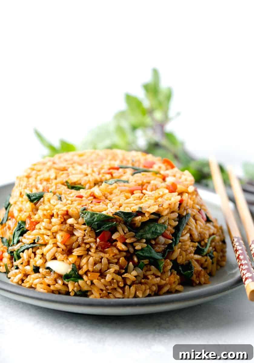 thai basil fried rice in a bowl mold on top of a grey ceramic plate with wooden chopsticks