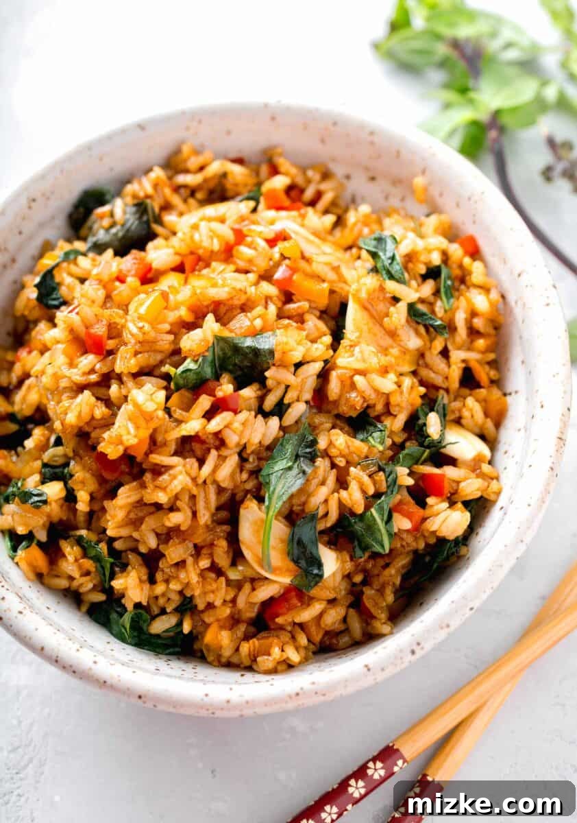 thai basil fried rice in a speckled ceramic bowl next to wooden chopsticks
